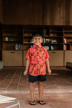 litte boy wearing aloha button up shirt with vibrant pink pua pattern