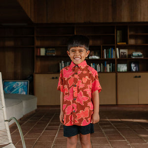 litte boy wearing aloha button up shirt with vibrant pink pua pattern