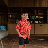 litte boy wearing aloha button up shirt with vibrant pink pua pattern