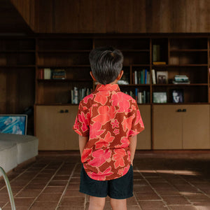 litte boy wearing aloha button up shirt with vibrant pink pua pattern