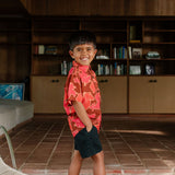 litte boy wearing aloha button up shirt with vibrant pink pua pattern