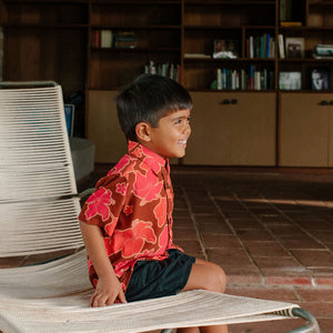 litte boy wearing aloha button up shirt with vibrant pink pua pattern