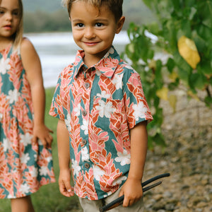 little boy wearing an aloha button up shirt with red ginger and tiare print