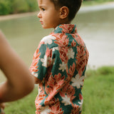 little boy wearing an aloha button up shirt with red ginger and tiare print