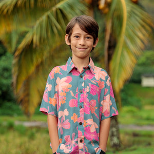 little boy wearing a teal button up aloha shirt with floral pattern