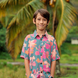 little boy wearing a teal button up aloha shirt with floral pattern