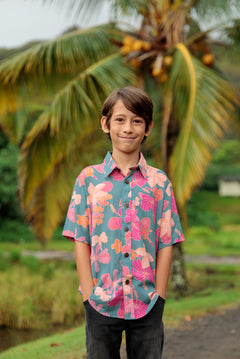 little boy wearing a teal button up aloha shirt with floral pattern