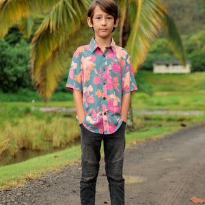 little boy wearing a teal button up aloha shirt with floral pattern