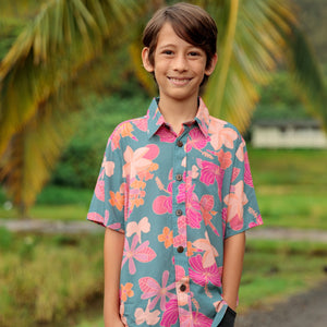 little boy wearing a teal button up aloha shirt with floral pattern