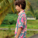 little boy wearing a teal button up aloha shirt with floral pattern