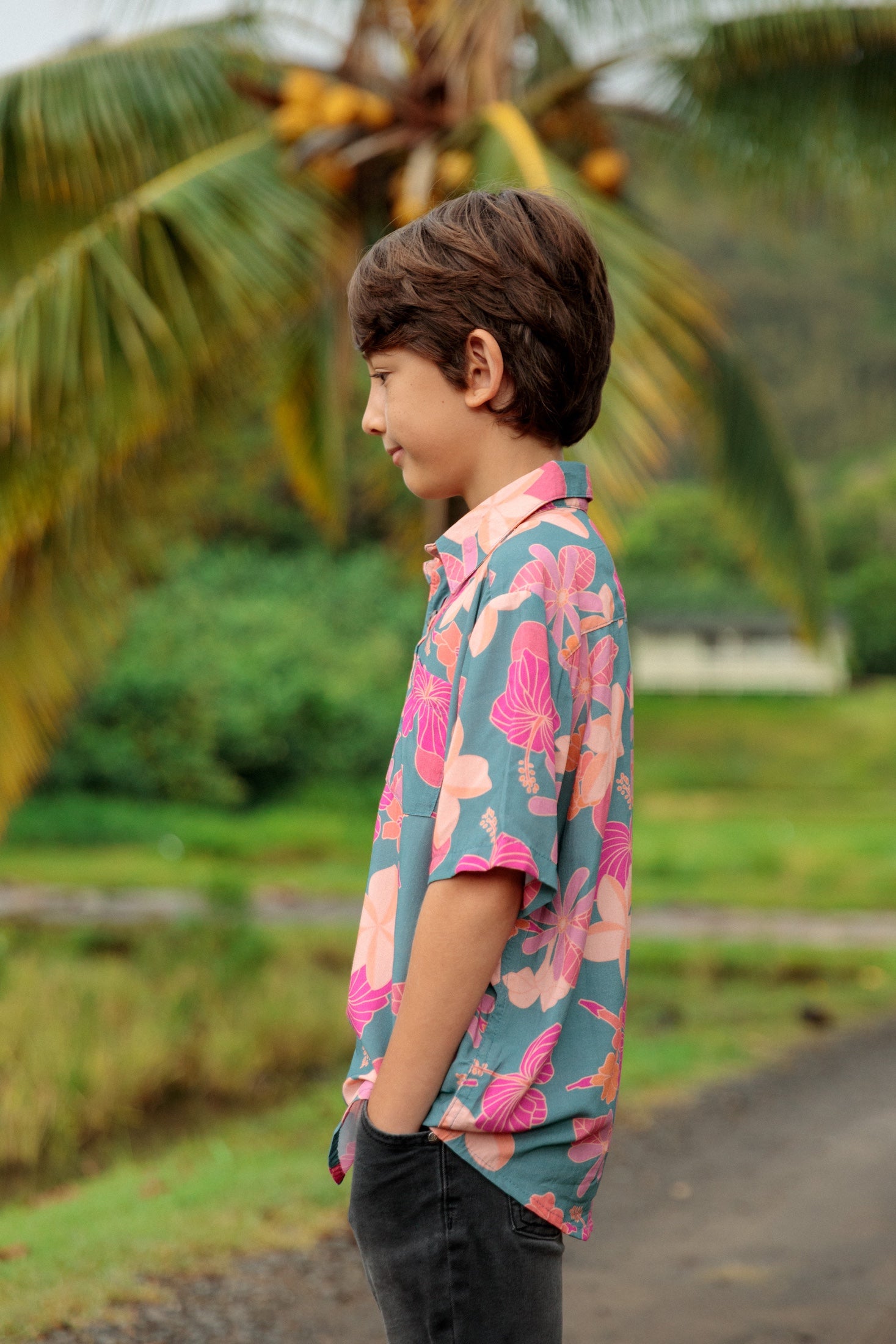 little boy wearing a teal button up aloha shirt with floral pattern