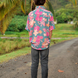 little boy wearing a teal button up aloha shirt with floral pattern