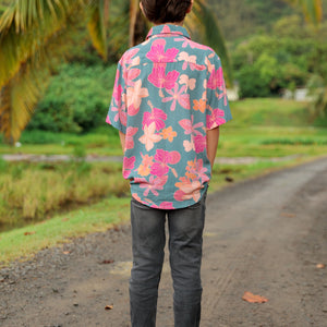 little boy wearing a teal button up aloha shirt with floral pattern