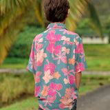 little boy wearing a teal button up aloha shirt with floral pattern