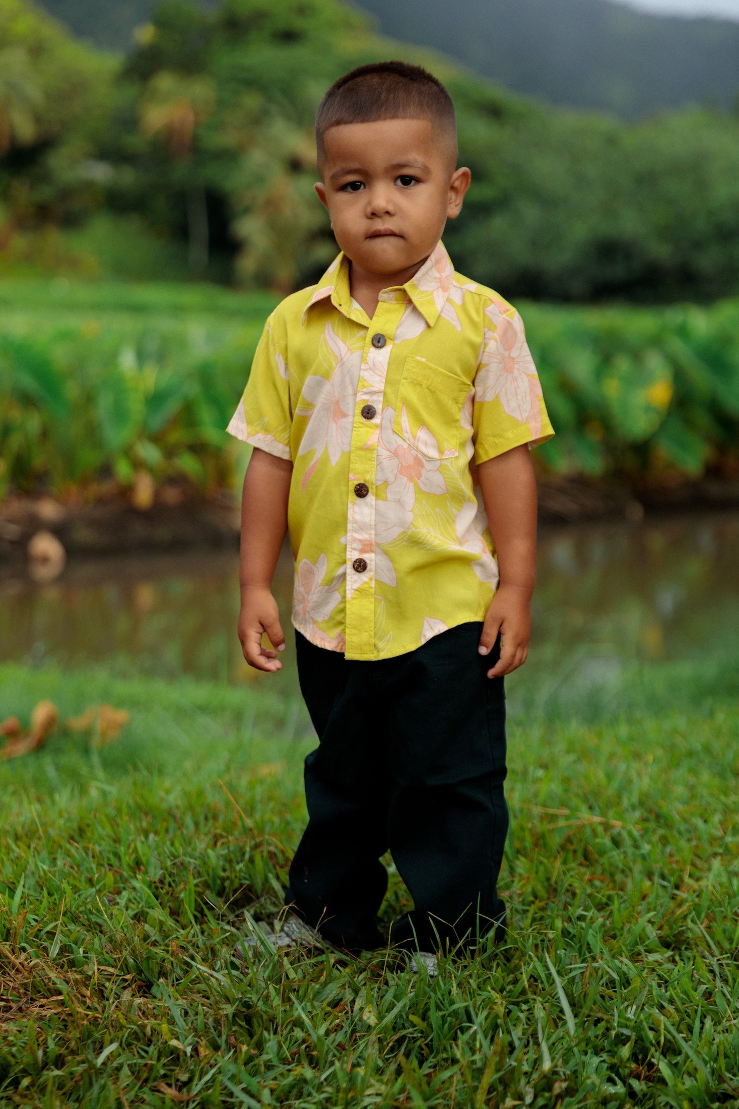 little boy wearing bright green aloha shirt with orchid print