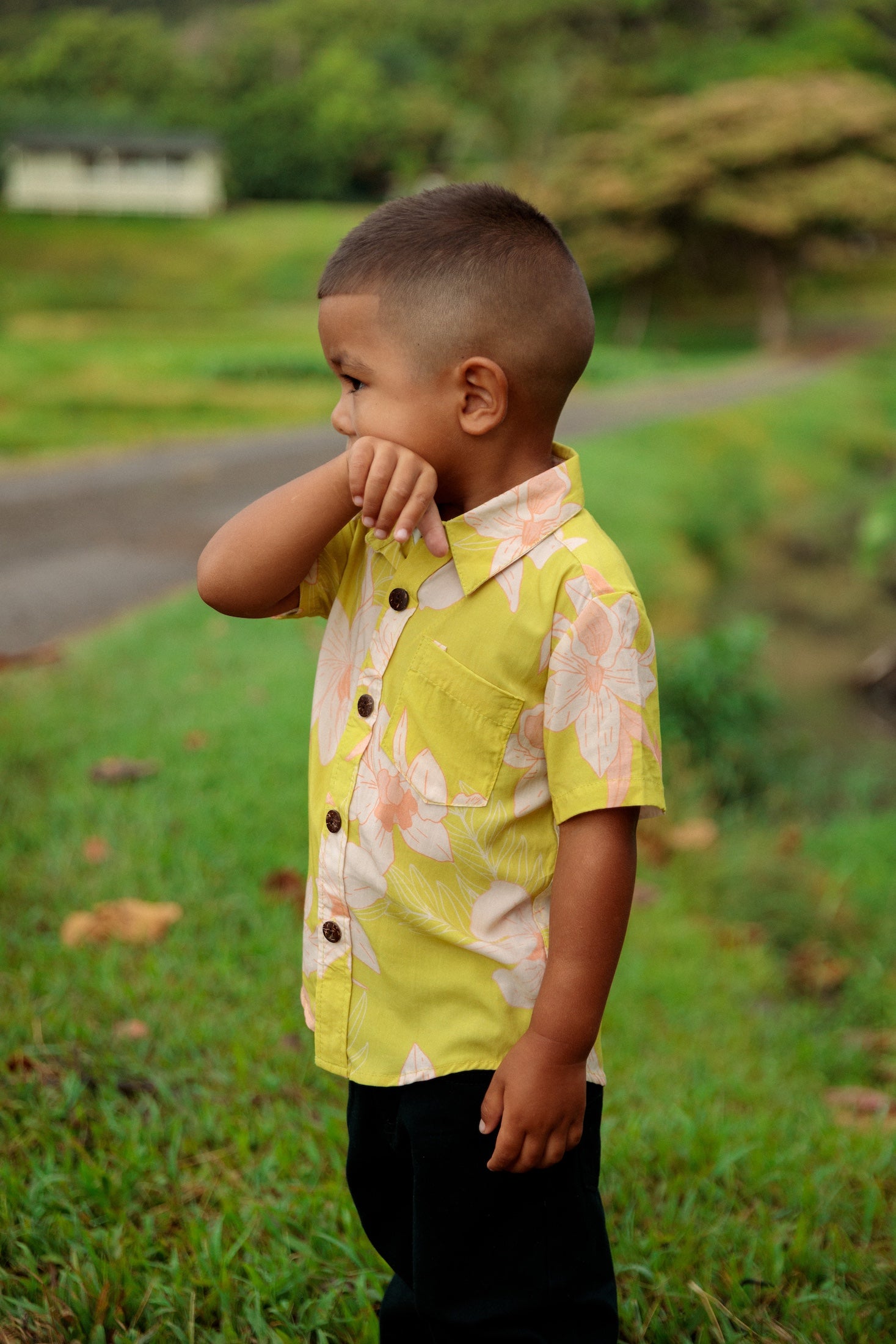 little boy wearing bright green aloha shirt with orchid print