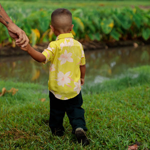 little boy wearing bright green aloha shirt with orchid print