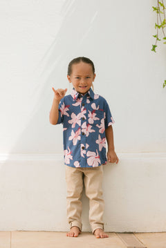 little boy wearing button up aloha shirt in navy and pink hibiscus print.