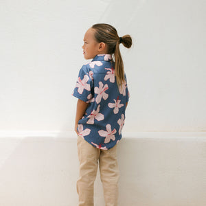little boy wearing button up aloha shirt in navy and pink hibiscus print.