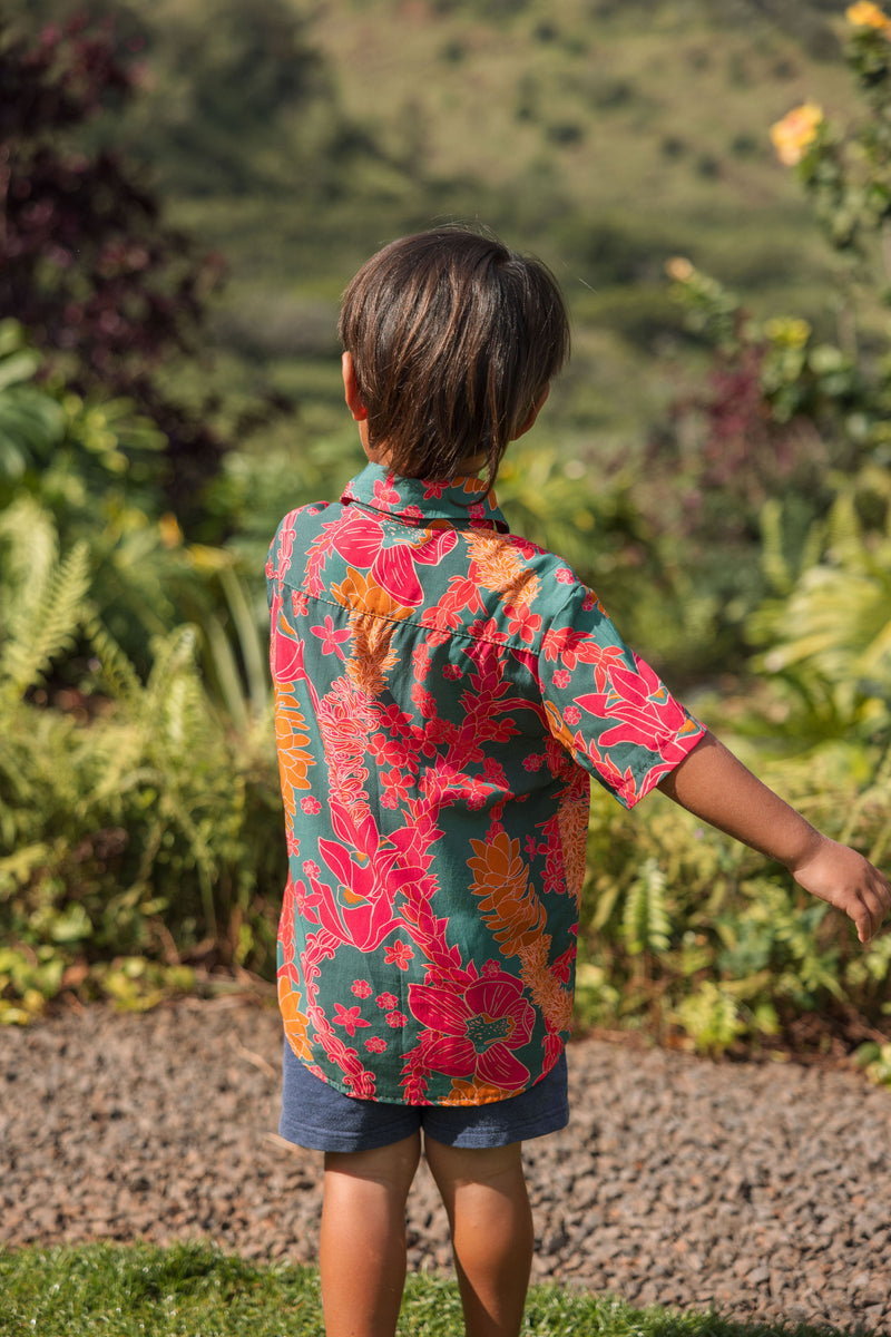 boy with brown hair wearing a colorful button up aloha shirt with tropical lei print