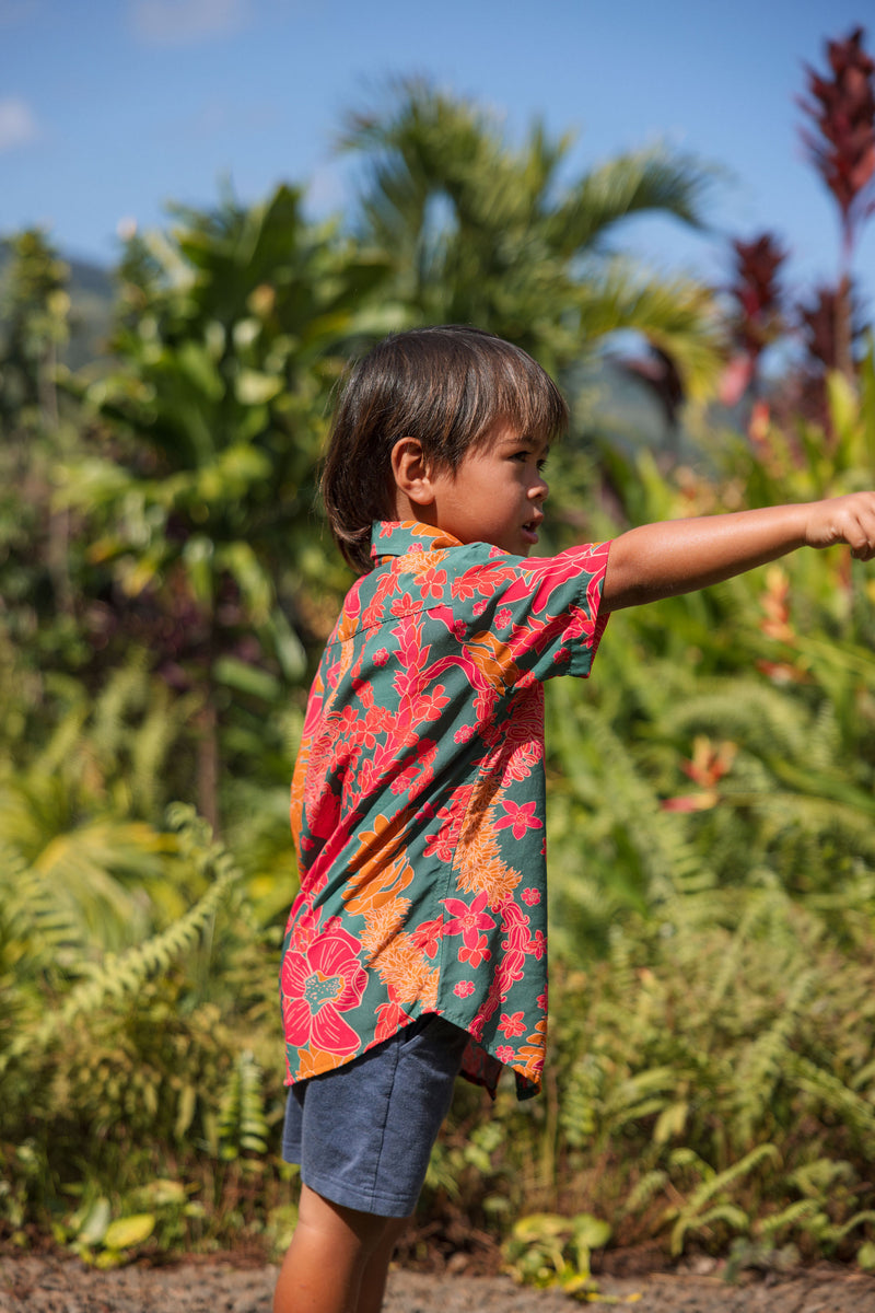 boy with brown hair wearing a colorful button up aloha shirt with tropical lei print
