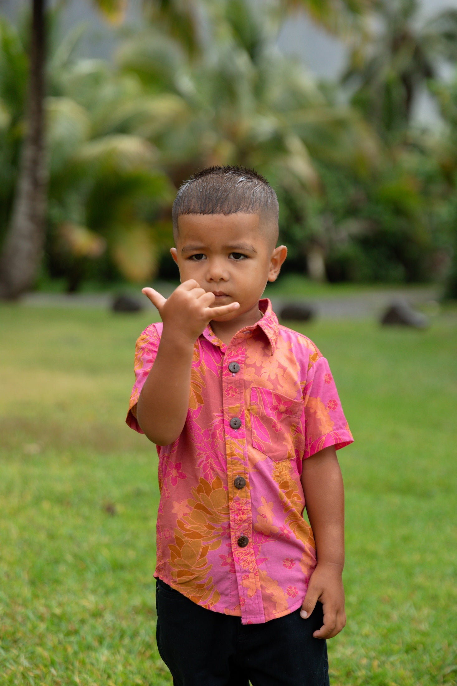 little boy wearing a mini aloha button up shirt in pink with lei pattern