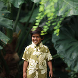little boy wearing mini aloha button up shirt in green print and naupaka pattern