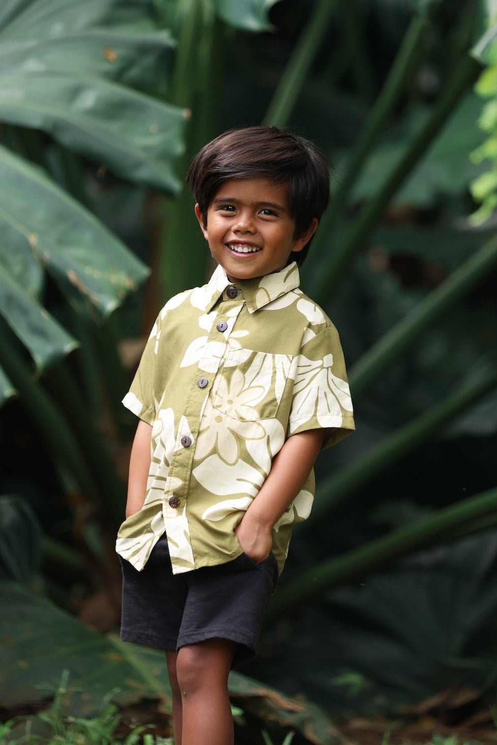 little boy wearing mini aloha button up shirt in green print and naupaka pattern