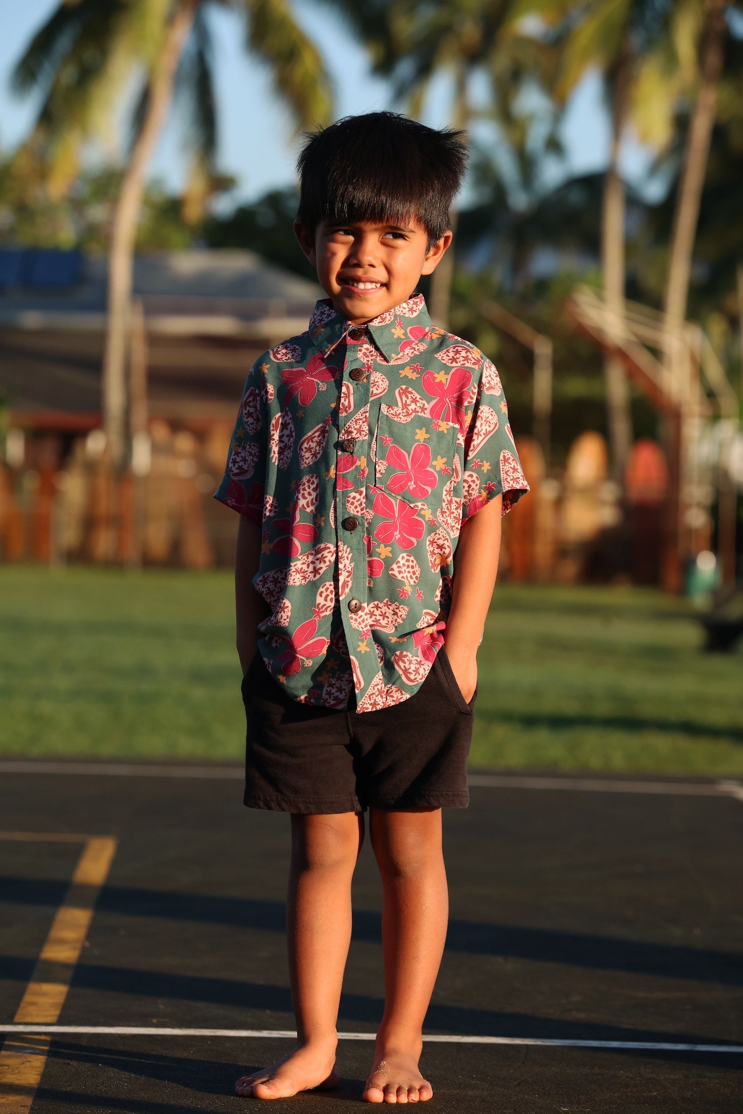 little boy wearing a teal aloha shirt with shell and pua print 