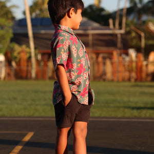 little boy wearing a teal aloha shirt with shell and pua print 