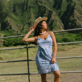 woman with brown hair wearing blue paisley printed slip dress