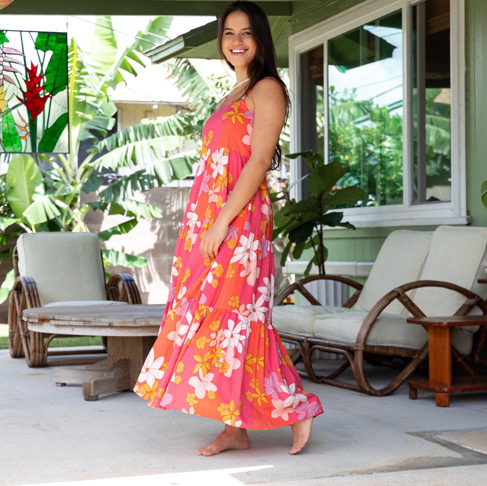 woman with brown hair wearing a pink maxi thin strap dress with retro flower print 