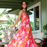 woman with brown hair wearing a pink maxi thin strap dress with retro flower print 