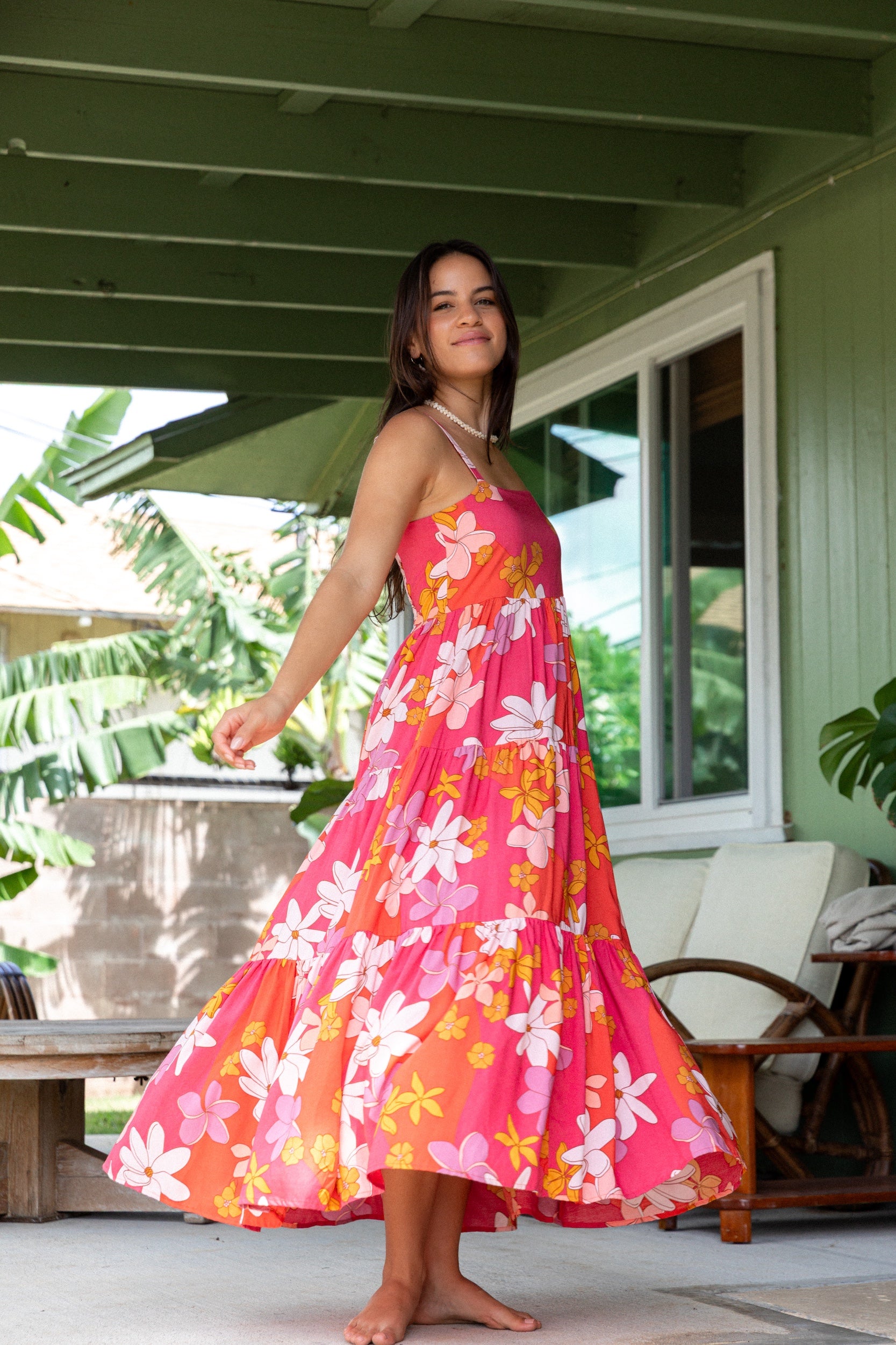 woman with brown hair wearing a pink maxi thin strap dress with retro flower print 