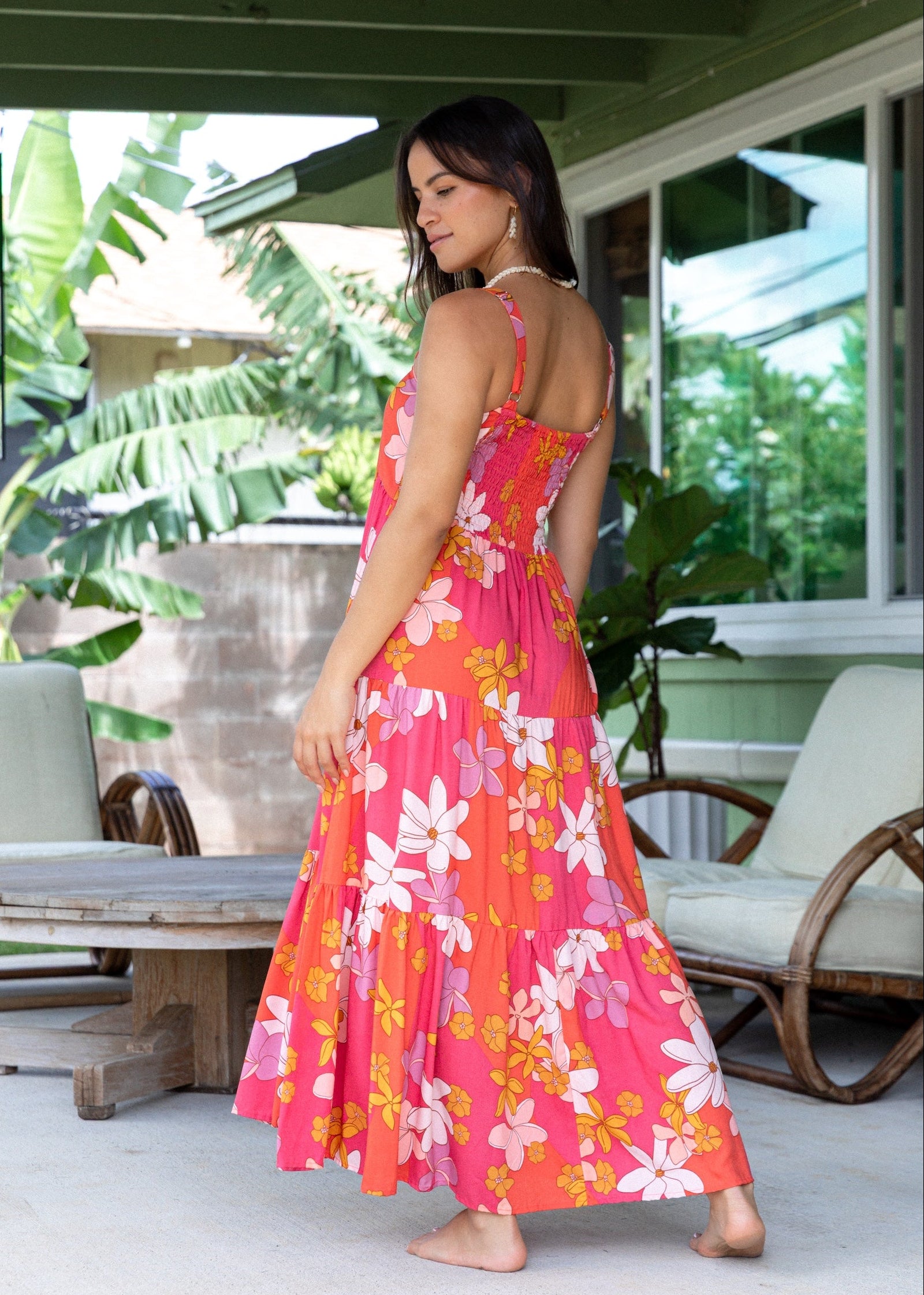 woman with brown hair wearing a pink maxi thin strap dress with retro flower print 