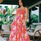 woman with brown hair wearing a pink maxi thin strap dress with retro flower print 