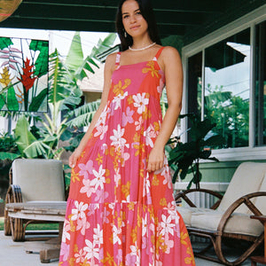 woman with brown hair wearing a pink maxi thin strap dress with retro flower print 