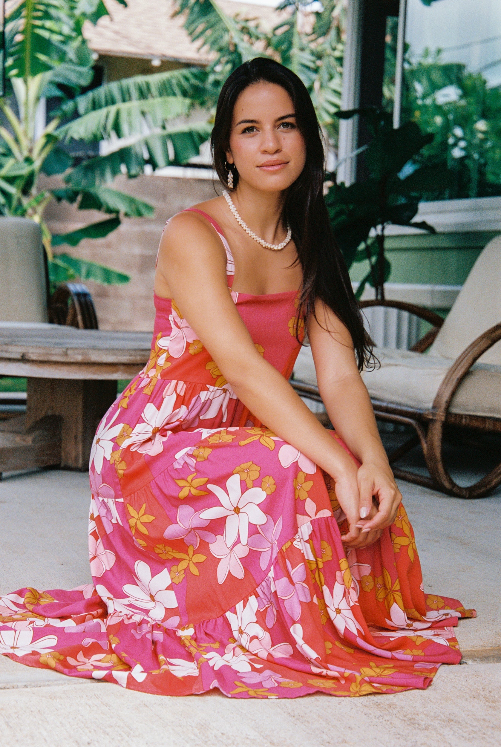 woman with brown hair wearing a pink maxi thin strap dress with retro flower print 