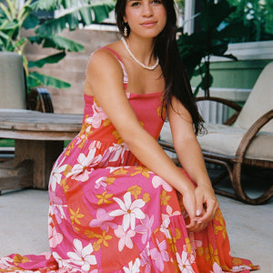 woman with brown hair wearing a pink maxi thin strap dress with retro flower print 