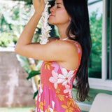 woman with brown hair wearing a pink maxi thin strap dress with retro flower print 