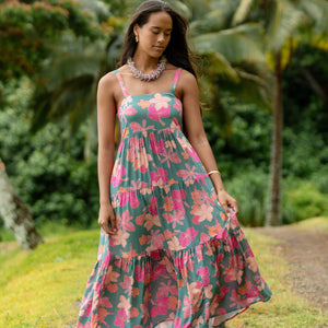 woman with brown hair wearing a teal maxi dress with orange and pink floral print