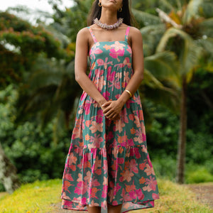 woman with brown hair wearing a teal maxi dress with orange and pink floral print