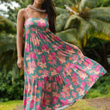 woman with brown hair wearing a teal maxi dress with orange and pink floral print
