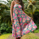 woman with brown hair wearing a teal maxi dress with orange and pink floral print