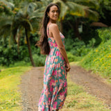 woman with brown hair wearing a teal maxi dress with orange and pink floral print