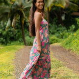 woman with brown hair wearing a teal maxi dress with orange and pink floral print