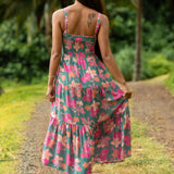 woman with brown hair wearing a teal maxi dress with orange and pink floral print