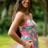 woman with brown hair wearing a teal maxi dress with orange and pink floral print