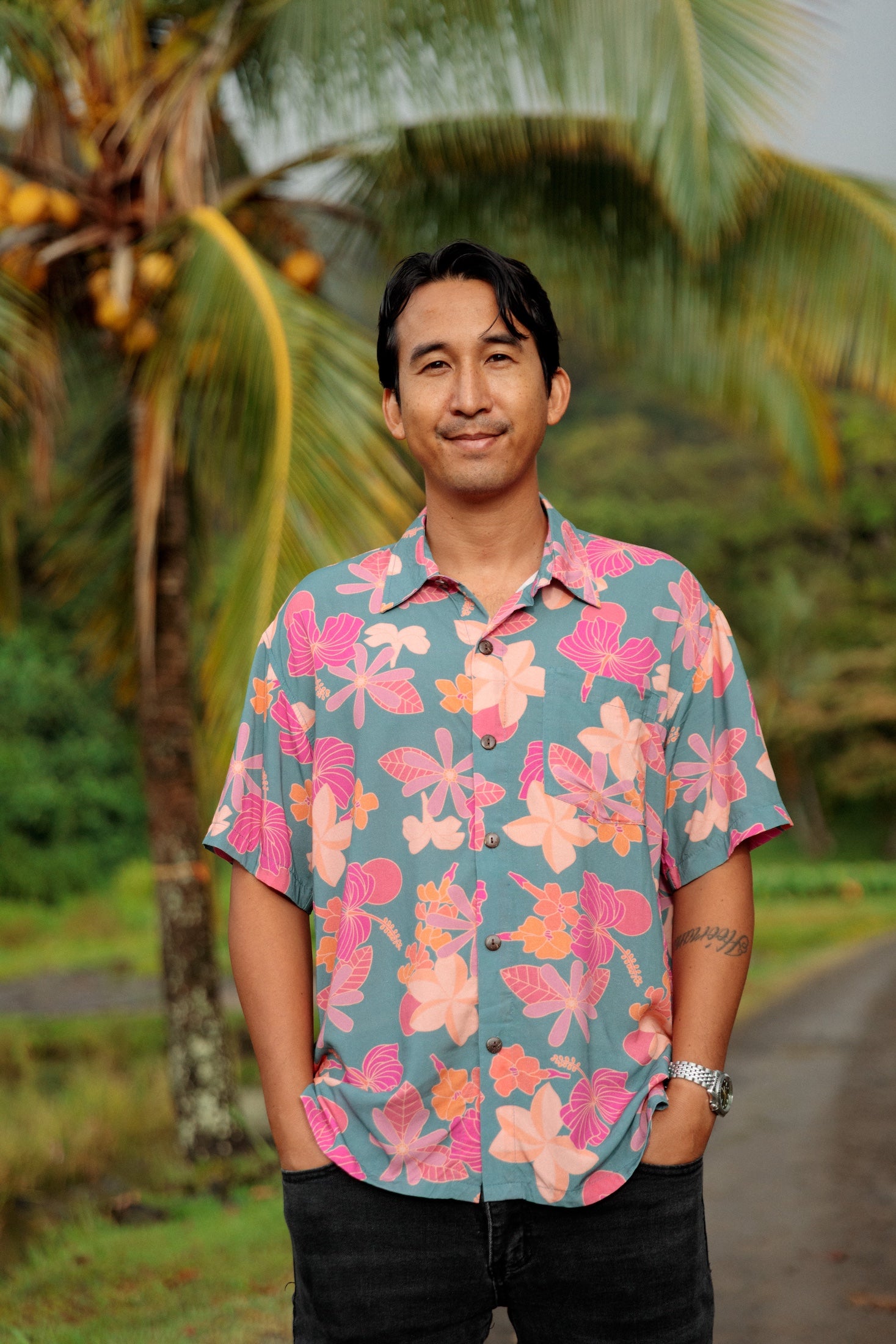 man wearing a teal aloha button up shirt with pink and orange floral pattern
