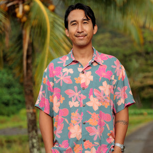 man wearing a teal aloha button up shirt with pink and orange floral pattern